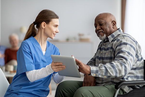 friendly-nurse-helping-black-senior-man-using-digital-tablet